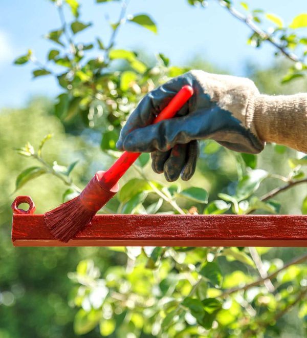 Young woman paints red primer metal structure